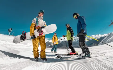 Grupa przyjaciół cieszy się jazdą na nartach i snowboardzie w marcu. Słońce świeci, a śnieg jest idealny do zjazdów.