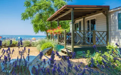 Idealne miejsce, gdzie na wakacje z dziećmi: domek letniskowy blisko plaży, z leżakami i kwitnącą lawendą.
