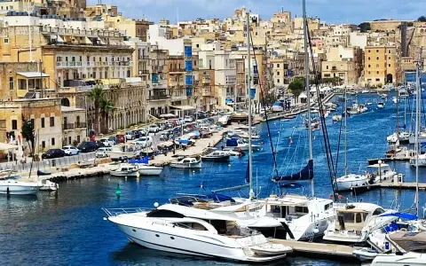 Malta plan zwiedzania: malowniczy port z łodziami i zabytkowymi budynkami w tle.