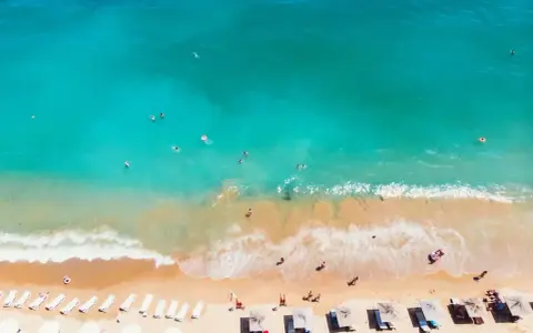 Słoneczna plaża w Bułgarii, turkusowe morze zaprasza do kąpieli. Leżaki i parasole czekają na plażowiczów.