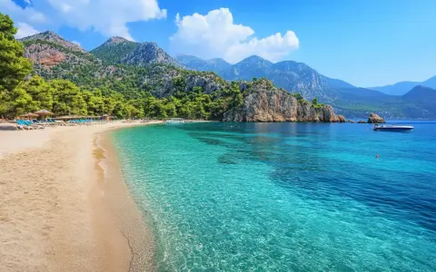 Piękna plaża w Turcji, Kusadasi, z turkusową wodą, górami i sosnami. Idealne miejsce na wakacje.