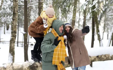 Rodzina robi sobie selfie w zimowym lesie. Idealne miejsce, gdzie na ferie z nastolatkiem, pełne śniegu i radości.