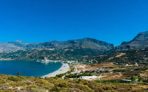 Malownicza zatoka z piaszczystą plażą i górami w tle. Urokliwe plaze Kreta zapraszają do odpoczynku.