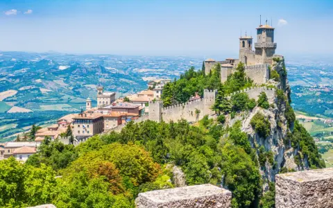 Trzy wieże obronne górują nad malowniczym krajobrazem San Marino, otoczone zielenią i historyczną zabudową.