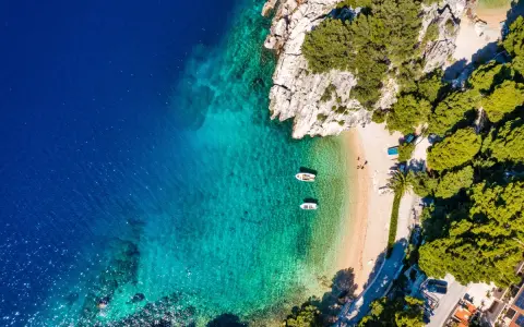 Widok z lotu ptaka na zatokę z krystalicznie czystą wodą, piaszczystą plażą i łodziami. Idealne miejsce na wakacje, jak z pocztówki z Chorwacji.