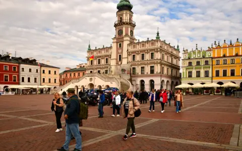 Rynek w Zamościu, idealne miejsce na wycieczki objazdowe z Lublina. Kolorowe kamienice i ratusz tworzą malowniczą scenerię dla spacerujących turystów.