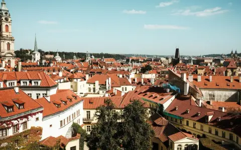 Widok na dachy Pragi, idealne miejsce na city break. W oddali wieże kościołów i wieża zegarowa.