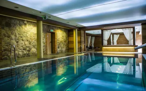 Basen w spa na Kaszubach. Kamienne ściany, turkusowa woda i zaciszne altany z białymi zasłonami tworzą atmosferę relaksu.
