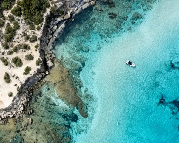 Plaża z turkusową wodą i łodzią, skaliste wybrzeże. Czy to Pafos czy Larnaka?