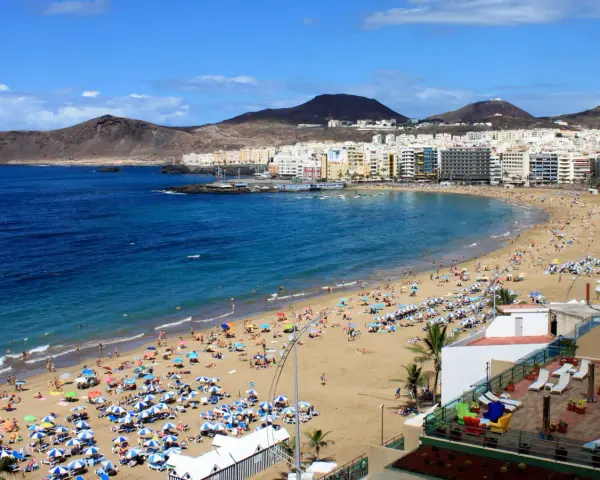 Słoneczna plaża Las Canteras na Gran Canarii, z turystami cieszącymi się ciepłą wodą. Idealna temperatura wody na Gran Canarii zachęca do kąpieli.