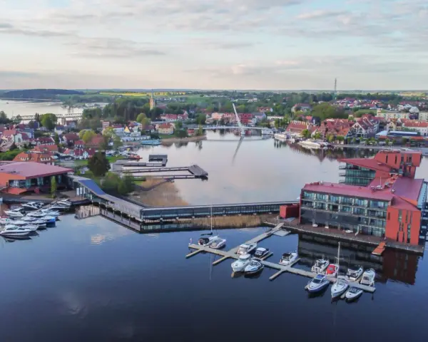 Malownicze Mazury: nowoczesna marina z hotelami i licznymi łodziami, idealne miejsce na relaks i odkrywanie atrakcji regionu.