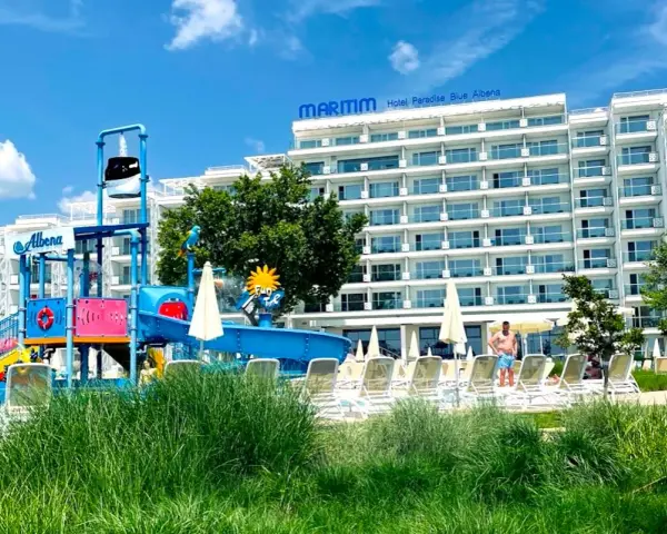 Kolorowy aquapark i hotel Maritim Paradise Blue Albena w Bułgarii, z leżakami i zieloną trawą.
