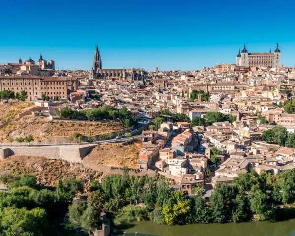 Widok na historyczne miasto Toledo w Hiszpanii, z katedrą i Alcázarem górującymi nad zabudowaniami.