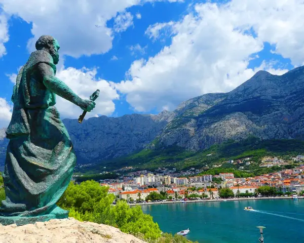 Pomnik na tle gór i miasta. Makarska atrakcje zachwycają widokiem na błękitne morze i skaliste szczyty.