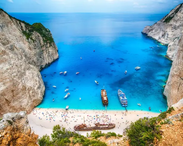 Zatoka Navagio, najcieplejsza wyspa grecka, z turkusową wodą, białym piaskiem, statkami i wrakiem.
