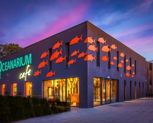 Oceanarium w Międzyzdrojach, jedna z głównych atrakcji, z neonowym napisem i pomarańczowymi rybkami na fasadzie.