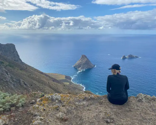 Widok na ocean z klifu, idealna teneryfa pogoda w grudniu. Kobieta w czapce podziwia skaliste wysepki.