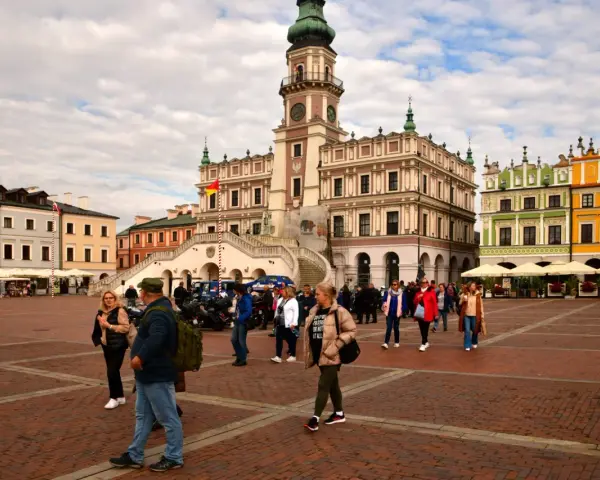 Rynek w Zamościu, idealne miejsce na wycieczki objazdowe z Lublina. Kolorowe kamienice i ratusz tworzą malowniczą scenerię dla spacerujących turystów.