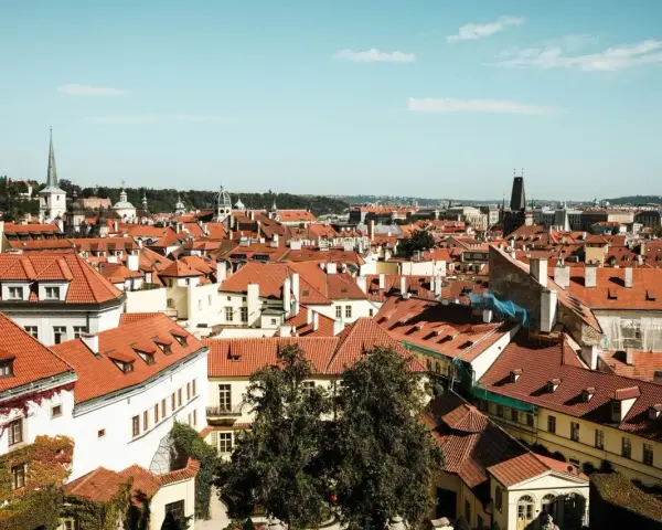 Widok na dachy Pragi, idealne miejsce na city break. W oddali wieże kościołów i wieża zegarowa.