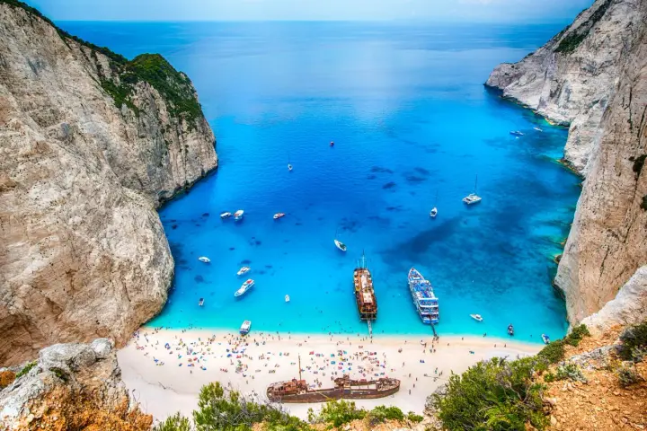 Zatoka Navagio, najcieplejsza wyspa grecka, z turkusową wodą, białym piaskiem, statkami i wrakiem.