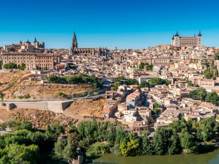 Widok na historyczne miasto Toledo w Hiszpanii, z katedrą i Alcázarem górującymi nad zabudowaniami.