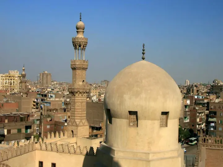 Widok na kopułę i minaret meczetu w Kairze, stolicy Egiptu, na tle miejskiego krajobrazu.