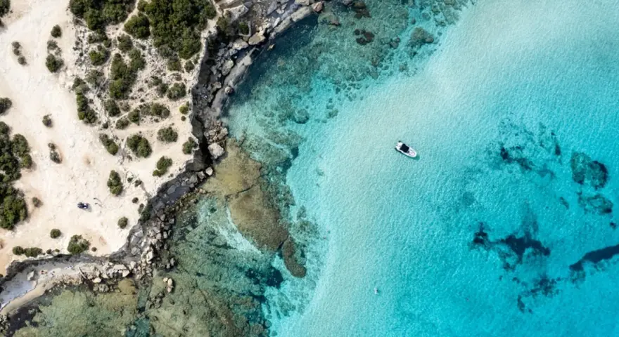 Plaża z turkusową wodą i łodzią, skaliste wybrzeże. Czy to Pafos czy Larnaka?