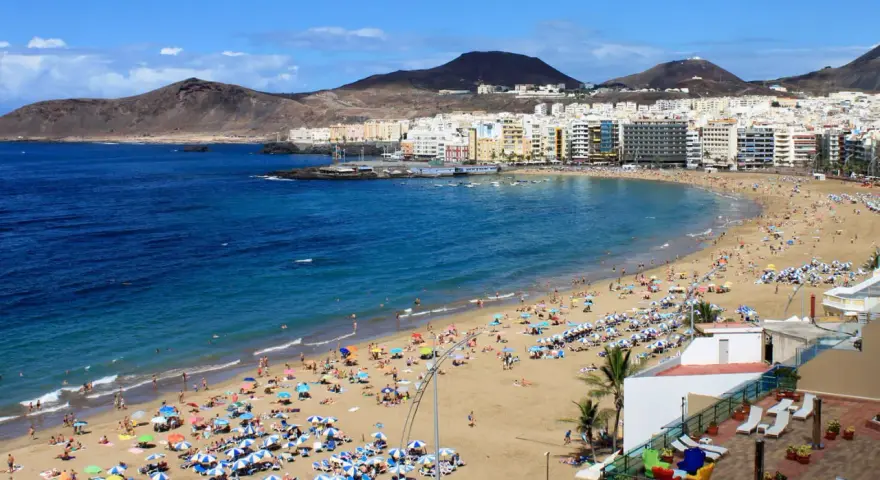 Słoneczna plaża Las Canteras na Gran Canarii, z turystami cieszącymi się ciepłą wodą. Idealna temperatura wody na Gran Canarii zachęca do kąpieli.