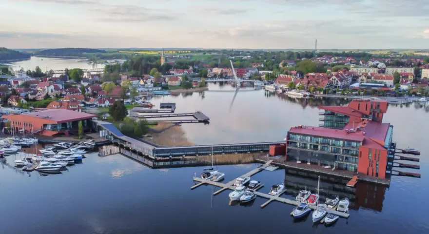 Malownicze Mazury: nowoczesna marina z hotelami i licznymi łodziami, idealne miejsce na relaks i odkrywanie atrakcji regionu.