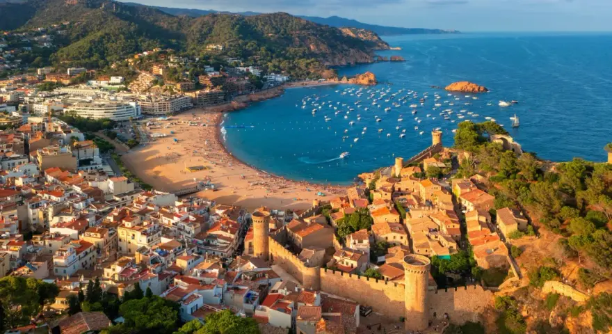 Widok na średniowieczne miasteczko z zamkiem i zatokę pełną łodzi. To idealne miejsce na odkrywanie atrakcji Costa Brava.