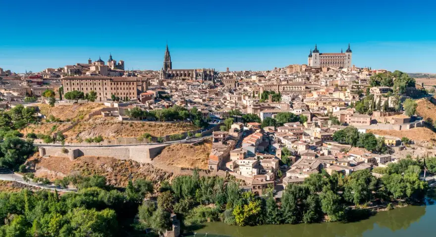 Widok na historyczne miasto Toledo w Hiszpanii, z katedrą i Alcázarem górującymi nad zabudowaniami.
