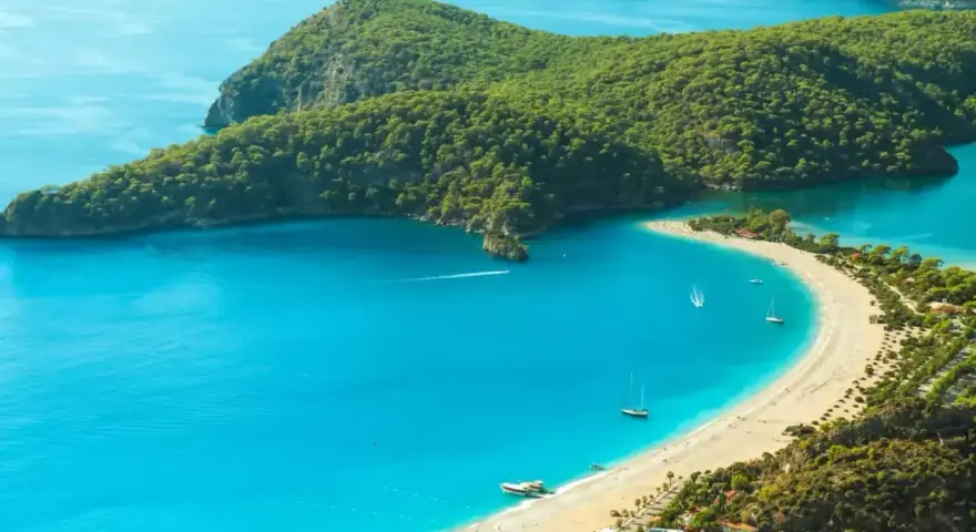 Idealne wakacje w listopadzie: turkusowa woda, piaszczysta plaża i zielone wzgórza.