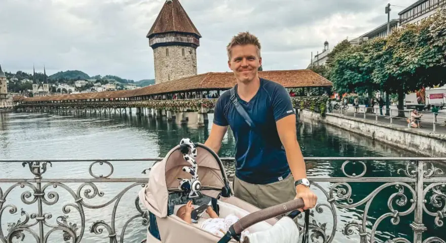Szczęśliwy ojciec z niemowlakiem w wózku na moście, idealne miejsce, gdzie na wakacje z niemowlakiem.