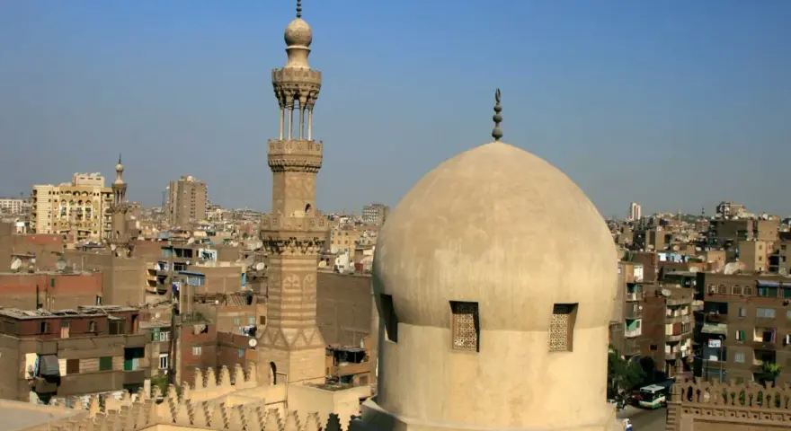Widok na kopułę i minaret meczetu w Kairze, stolicy Egiptu, na tle miejskiego krajobrazu.