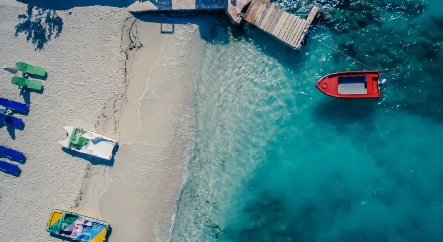 Idealne miejsce, gdzie na wakacje w styczniu: pusta plaża, łódki czekają na wodzie, a słońce grzeje.