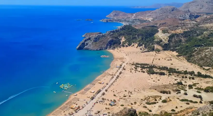 Malownicze plaże Rodos z turkusową wodą, piaszczystym wybrzeżem, leżakami i wodnym parkiem rozrywki.