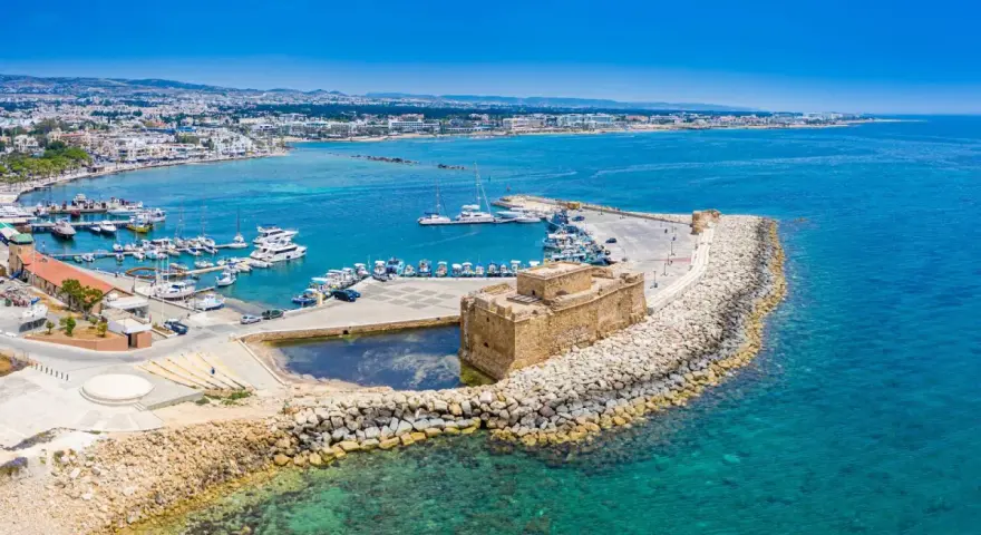 Pafos pogoda: Słoneczny dzień nad portem z zamkiem, jachtami i miastem w tle. Idealna pogoda na zwiedzanie Cypru.