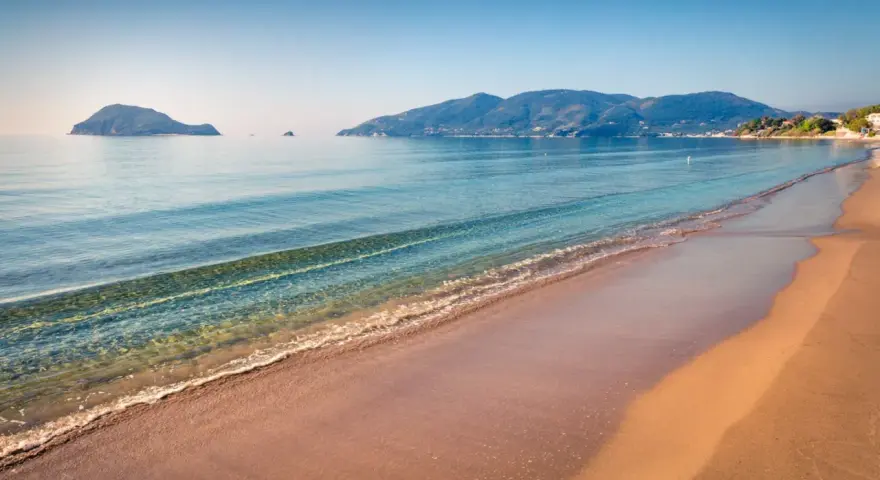 Spokojna plaża Caretta z łagodnymi falami i wyspami w oddali. Idealne miejsce na relaks.