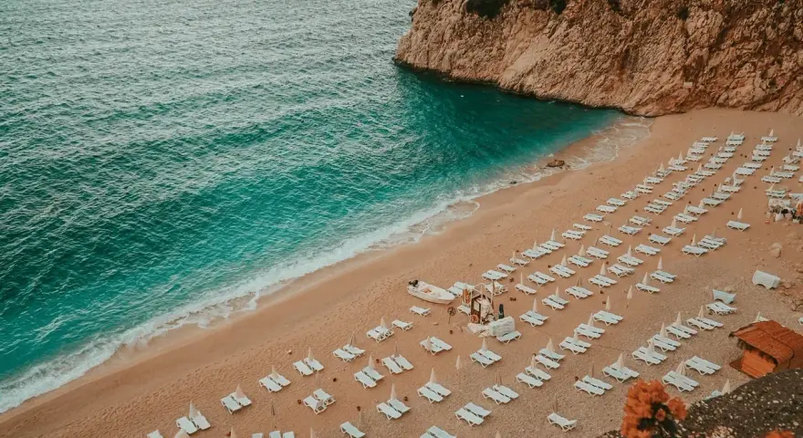 Piękna plaża z leżakami i turkusową wodą. Idealne miejsce, by zapytać: Turcja gdzie na wakacje?