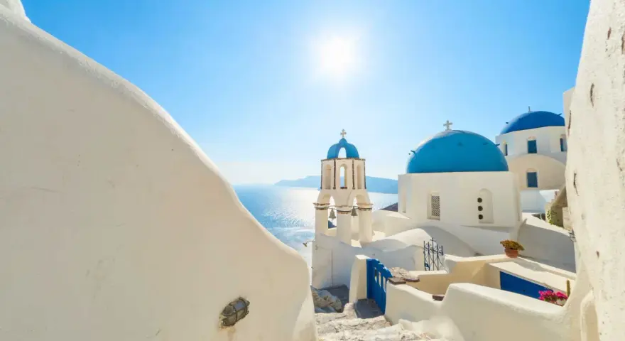 Santorini, październik. Słoneczna pogoda, białe domy i niebieskie kopuły kościołów nad Morzem Egejskim.