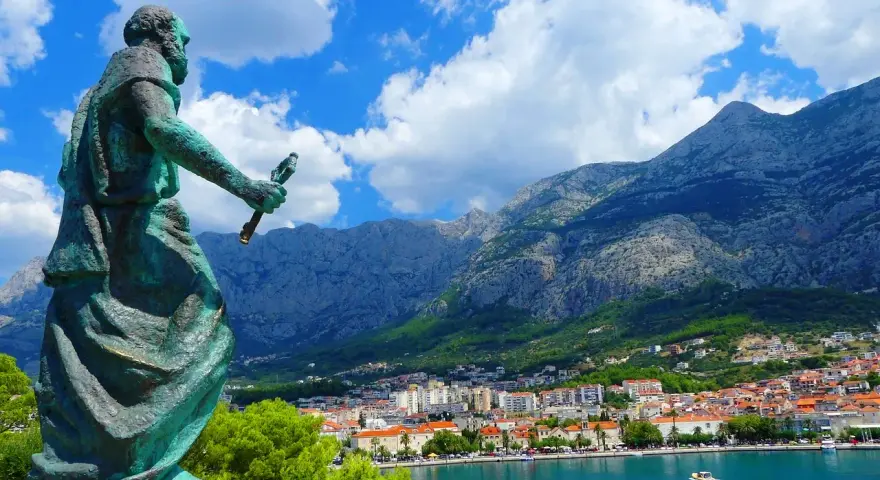 Pomnik na tle gór i miasta. Makarska atrakcje zachwycają widokiem na błękitne morze i skaliste szczyty.