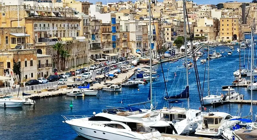 Malta plan zwiedzania: malowniczy port z łodziami i zabytkowymi budynkami w tle.