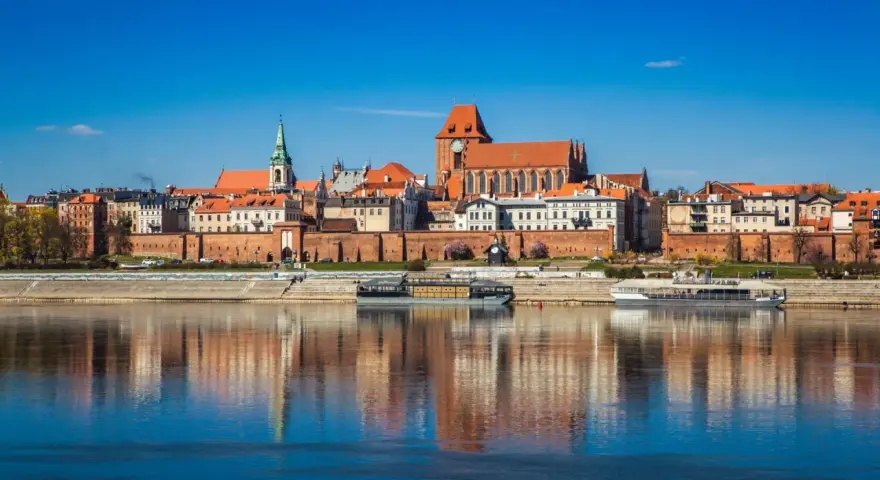 Widok na zabytkowe centrum Torunia z Wisłą w tle. Zobacz, co warto zobaczyć w Toruniu: katedrę, ratusz i średniowieczne mury.