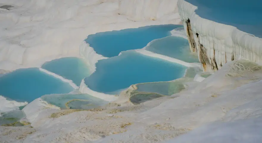 Turkusowe wody tworzą kaskady na białych tarasach wapiennych w Pamukkale w Turcji.