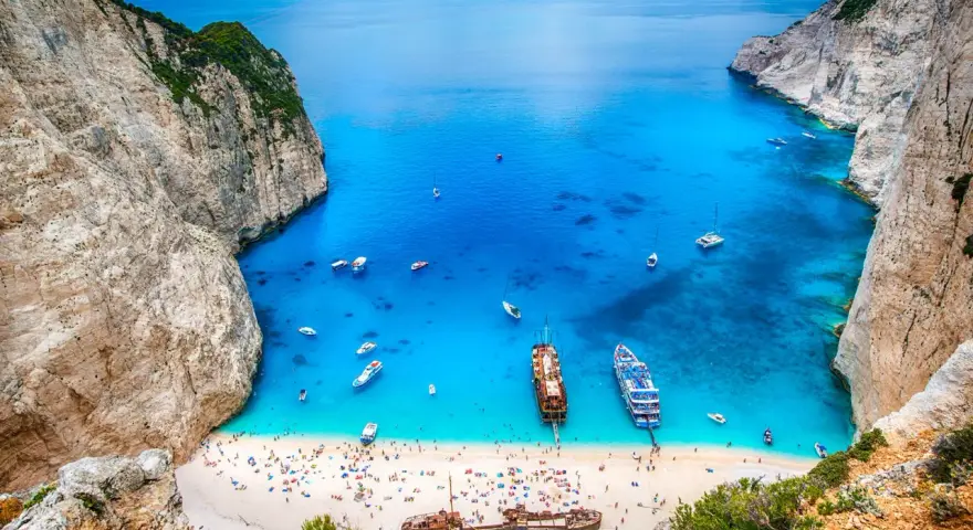 Zatoka Navagio, najcieplejsza wyspa grecka, z turkusową wodą, białym piaskiem, statkami i wrakiem.