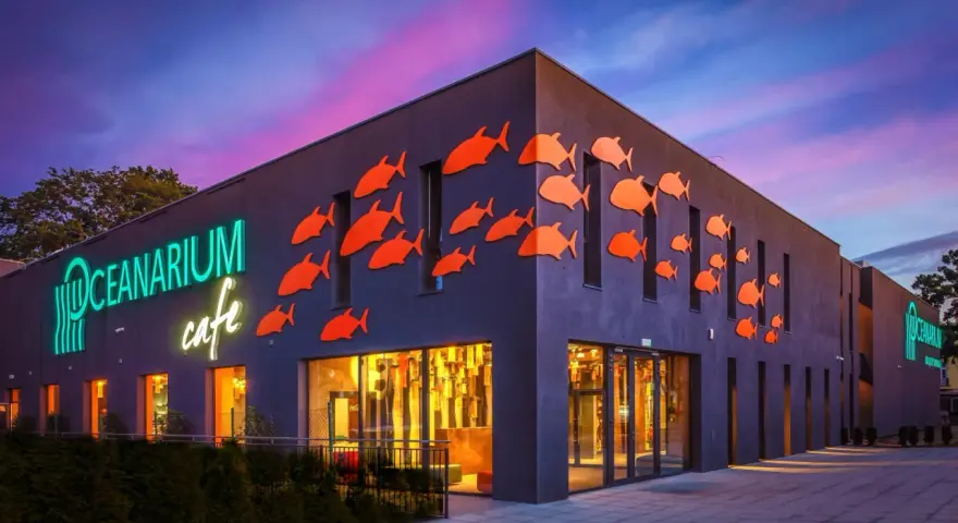 Oceanarium w Międzyzdrojach, jedna z głównych atrakcji, z neonowym napisem i pomarańczowymi rybkami na fasadzie.