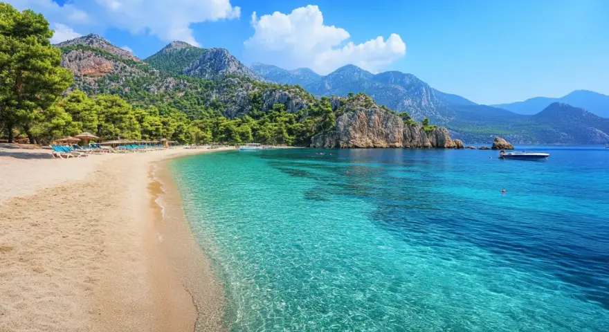 Piękna plaża w Turcji, Kusadasi, z turkusową wodą, górami i sosnami. Idealne miejsce na wakacje.