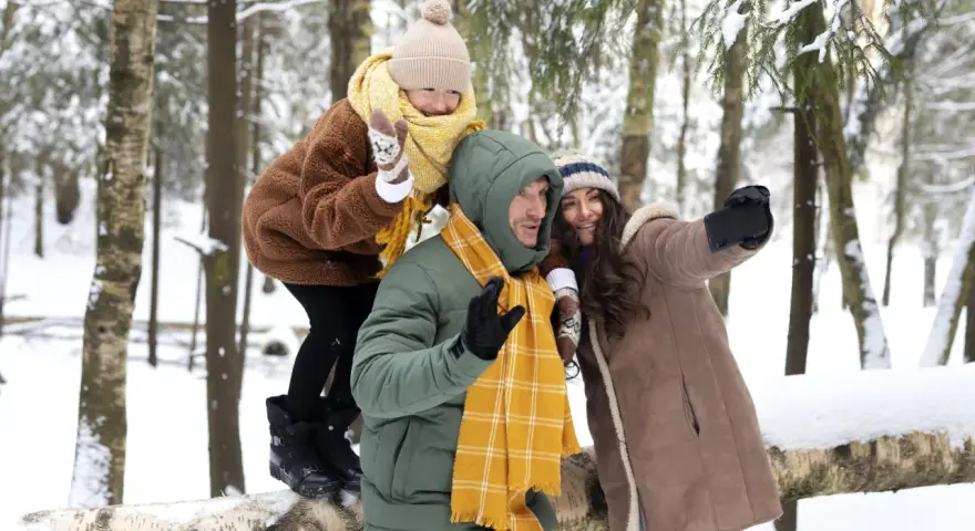 Rodzina robi sobie selfie w zimowym lesie. Idealne miejsce, gdzie na ferie z nastolatkiem, pełne śniegu i radości.