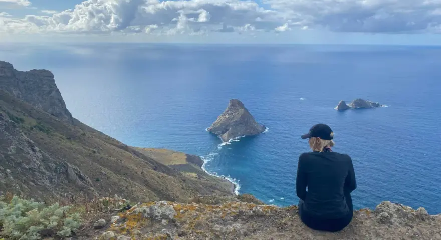 Widok na ocean z klifu, idealna teneryfa pogoda w grudniu. Kobieta w czapce podziwia skaliste wysepki.