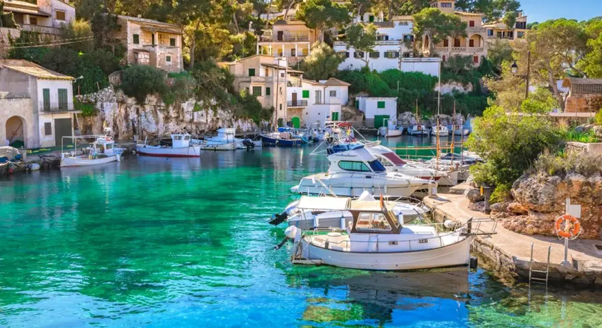 Malowniczy port na Balearach, gdzie turkusowa woda otacza zacumowane łodzie. Takie widoki oferują baleary, jakie wyspy zachwycają każdego!